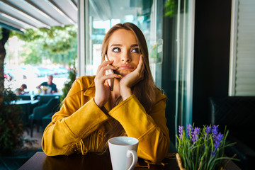 Portrait of young beautiful woman at cafe restaurant talking to the mobile phone call receiving boring talk