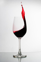 Red wine splashing up the side of a wineglass