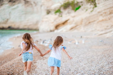 Little happy funny girls have a lot of fun at tropical beach playing together. Sunny day with rain in the sea