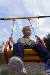 boy child rides on a swing in the playground in summer © bo.kvk