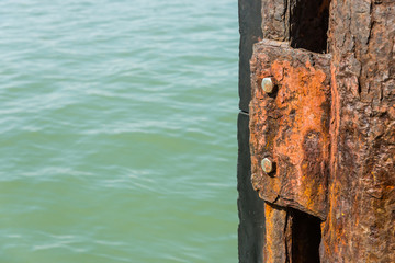 Close up image of damage rusty steel plate with stainless nuts in the sea