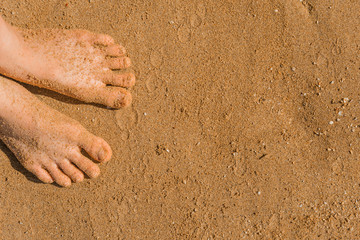 Close up image of human foots on brown sand beach