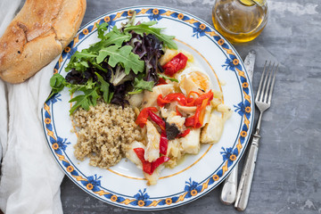 cod fish with quinoa and fresh salad on dish and olive oil