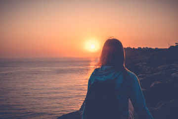 Fototapeta premium Girl watching the sunset on the ocean
