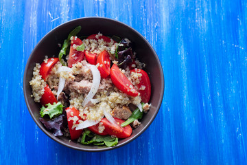 salad quinoa with tuna, tomato and lettuce in brown bowl