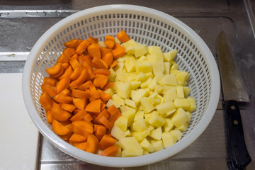 ザルの中の切った人参とジャガイモ