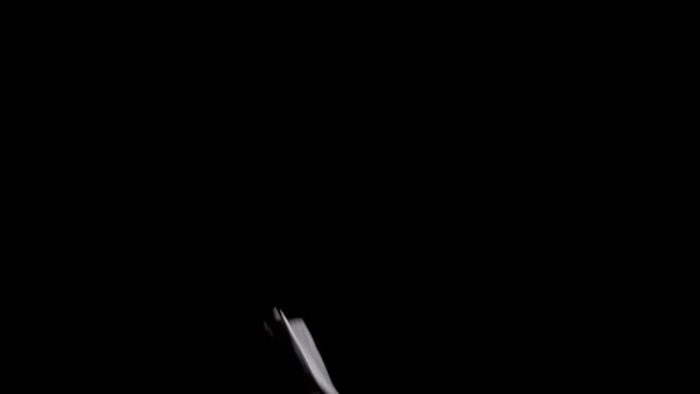 Handkerchiefs falling in slow motion in front of a black background.