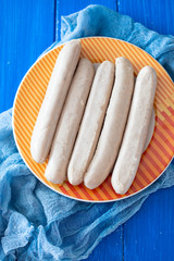 fresh sausages on orange dish on wooden background