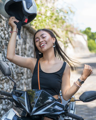 Fototapeta na wymiar Asian girl in a black dress on a scooter. Beautiful Balinese women lifestyle portrait