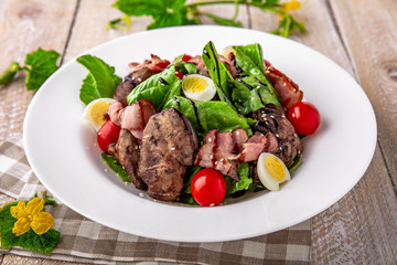 Hot salad of liver and ham with quail eggs, cherry tomatoes and herbs with balsamic sauce on white boards. Free space for text. Menu cover