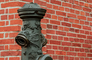 Vintage black hydrant on a background of red brick wall.