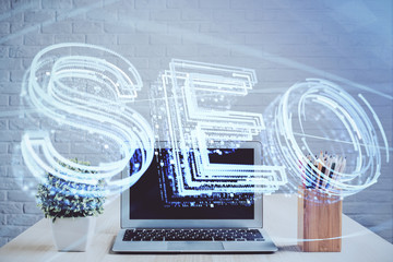 Double exposure of table with computer and seo drawing hologram. Search optimization concept.