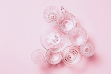 Many empty glasses on pink background. Top view, flat lay.