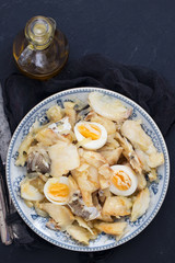 cod fish with onion, eggs and olive oil on dish