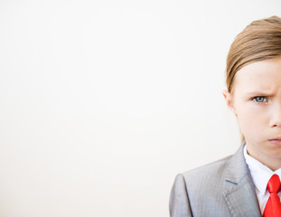 Fragment of a child's face in a business suit and a red tie on a white background
