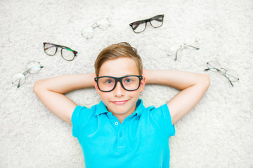 Happy handsome child boy trying on glasses. Health, medicine and ophthalmology concept