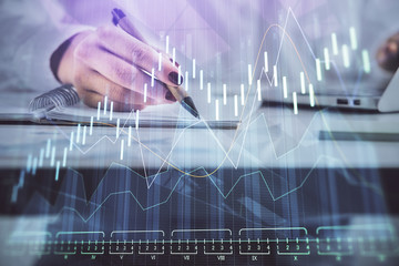 Double exposure of woman's hands making notes with forex graph hologram. Concept technical analysis.