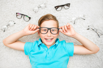 Happy handsome child boy trying on glasses. Health, medicine and ophthalmology concept
