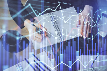 Forex chart hologram on hand taking notes background. Concept of analysis. Multi exposure