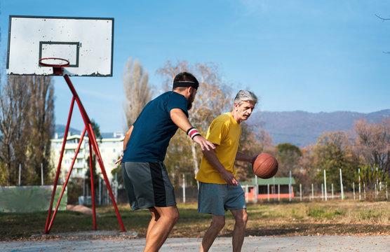 Senior Man Playing Basketball With His Son In A Park