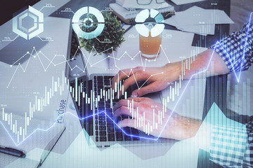 Double exposure of graph with man typing on computer in office on background. Concept of hard work.