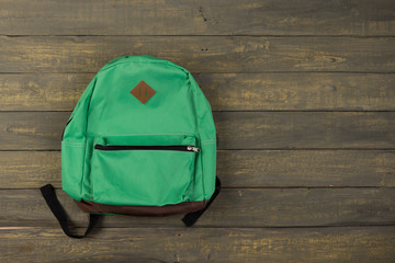 Back to school concept - green backpack on wooden backgroung,