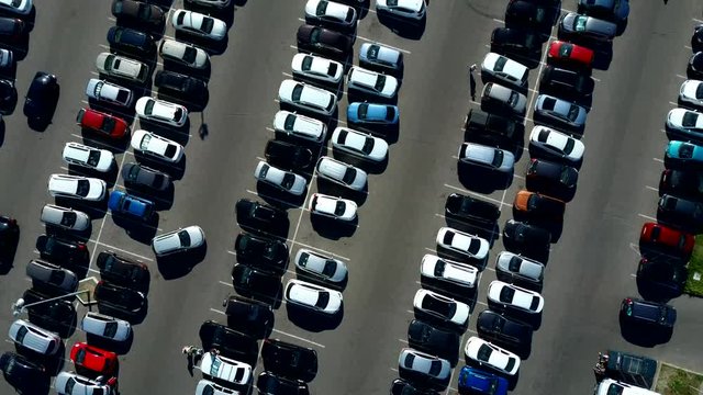 A view from above to the process of car parking. Heavy traffic in the parking lot. Searching for spaces in the busy car park. Parking advice. Cruising for parking in busy business center