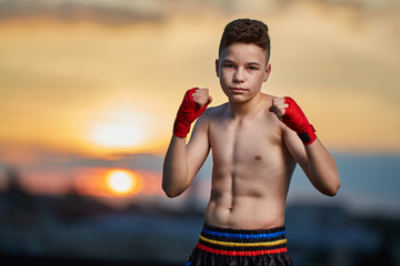 Young fighter training on the roof at sunset