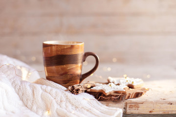 Christmas still life. Mug of hot steamy tea, gingerbread cookies at wooden background with glares. Cozy morning breakfast with homemade sweets and cup of coffee. Winter food, drinks, new year lights.