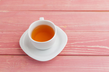 White porcelain tea cup with saucer on pink wooden background top view