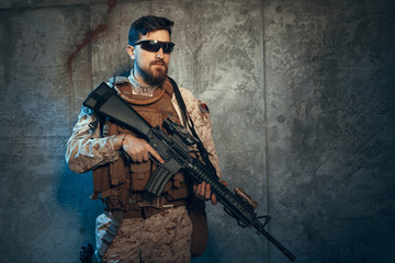 Fototapeta premium Young man in military outfit a mercenary soldier in modern times on a dark background in studio