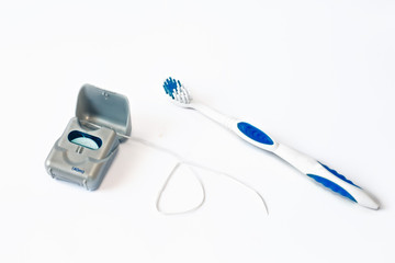 Plastic toothbrush and dental floss on white background with empty space for image or text. Toothbrush and hygienic dental thread for personal dental care. Dentistry. Toothbrush. Close-up