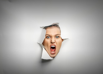 Woman looking out from a hole of torn paper