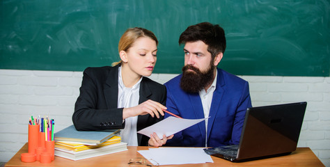 School educator with laptop and principal with official documents. School education. Take into account educational norms. Prepare for school lesson. Teacher and supervisor working in school classroom