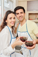 Portrait joyful young couple toasting with wine glasses and looking at camera