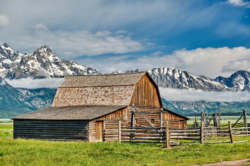 Fototapeta na wymiar Old mormon barn in Grand Teton Mountains with low clouds. Grand Teton National Park, Wyoming, USA.