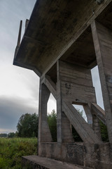an unfinished bridge stands on the river in the meadow