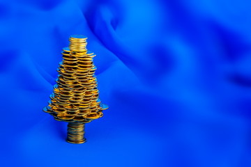 Golden happy  Christmas tree with  many golden coins on blue blur background, business metaphor   