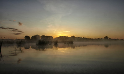 sunrise above a river on foggy summer morning, the sky reflections in the water,  misty reflection in steaming water, Salaca river, Latvia 