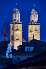 Fototapeta na wymiar Zürich Grossmünster zur blauen Stunde, beleuchtete Zwillingstürme, Dächer Altstadt, dunkelblauer Abendhimmel