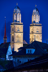 Fototapeta premium Zürich Grossmünster zur blauen Stunde, beleuchtete Zwillingstürme, Dächer Altstadt, dunkelblauer Abendhimmel