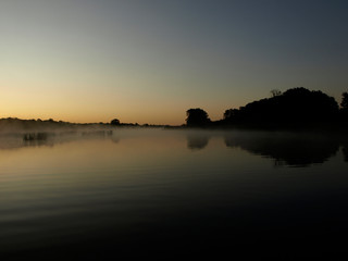 sunrise above a river on foggy summer morning, the sky reflections in the water,  misty reflection in steaming water, Salaca river, Latvia 