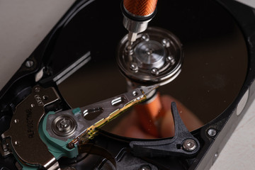 A teenager disassembles the hard drive of a computer to study its device.