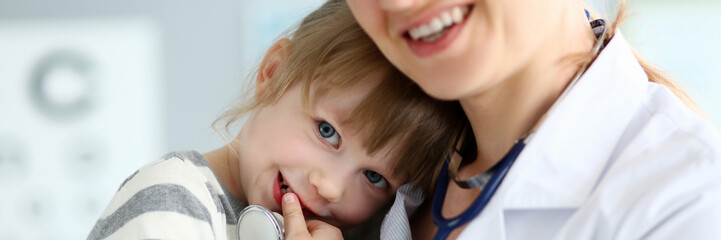 Paediatric doctor holding and hugging little cute girl patient portrait