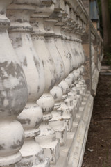 Antique balusters of gray color with cracked white paint. Linear perspective. Creative vintage background. Balustrade.