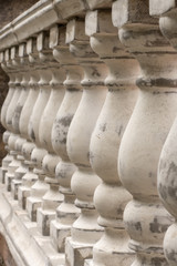 Antique balusters of gray color with cracked white paint. Linear perspective. Creative vintage background. Balustrade.
