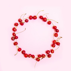 Frame made of sweet cherries on light on a pink background. Top view