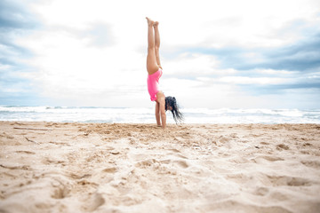 Fototapeta na wymiar Pretty girl doing gymnastics on the beach