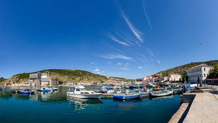 Fototapeta na wymiar The promenade of the city of Balaklava on a bright sunny day with many parked yachts and boats.