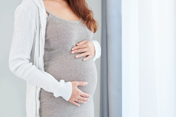Croppred image of young woman anticipating baby touching her baby bump